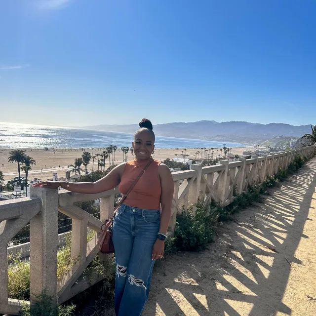 Travel Advisor Ke'Aundra Murray in an orange top with beach in the background. 