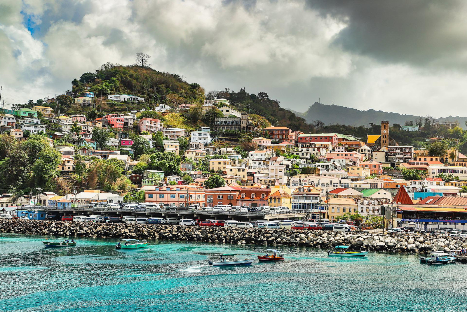 Colorful buildings with the ocean in the foreground and green hills in background in Grenada