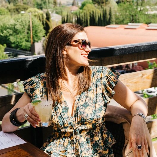 Travel Advisor Emily Martin with a floral dress holding a drink on a balcony.