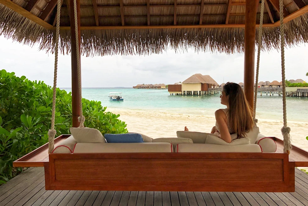 woman sitting on bench overlooking beach and water