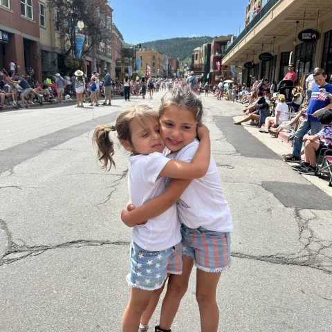 Two kids hugging each other on  a street.