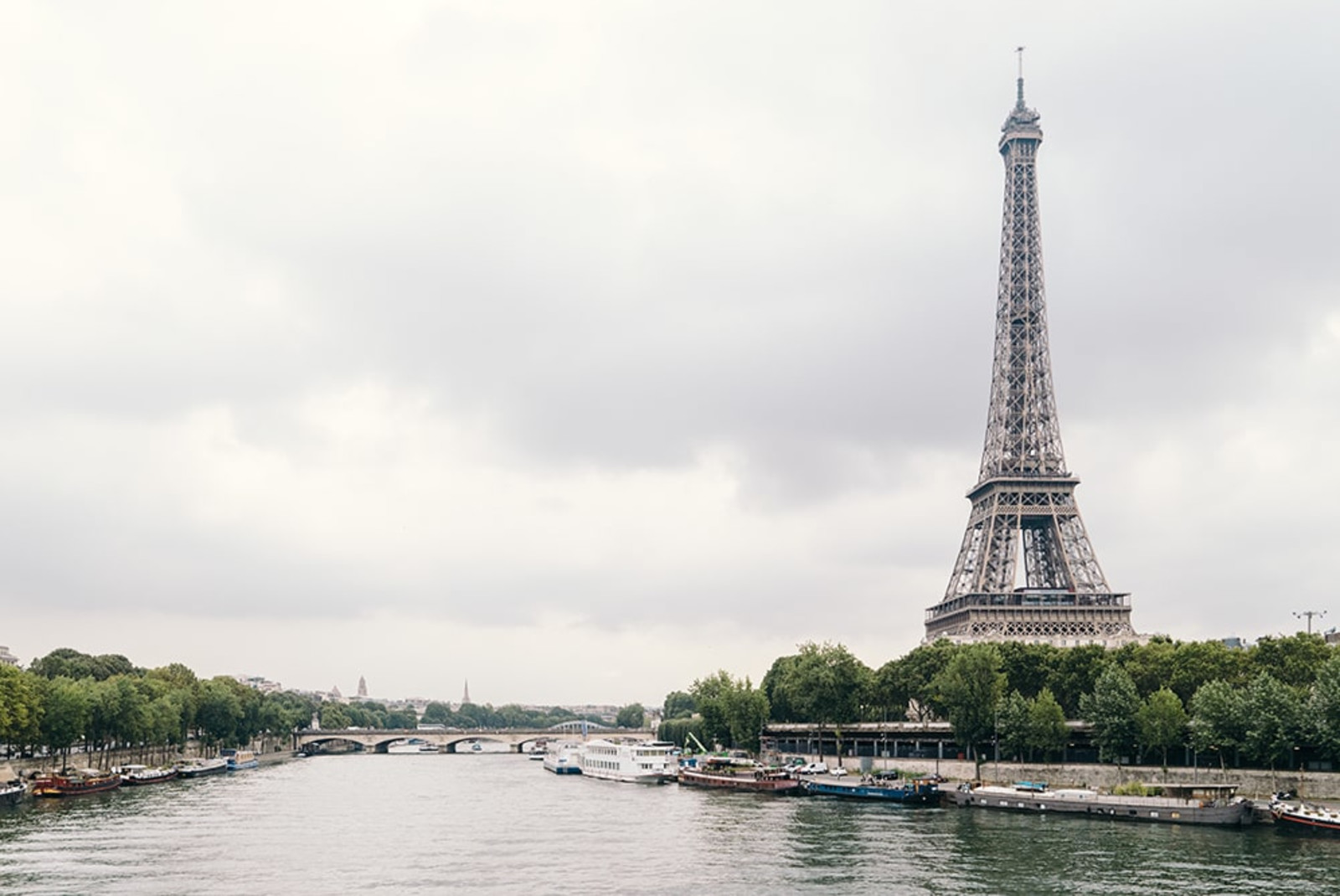 Effiel tower next to body of water with cloudy skies