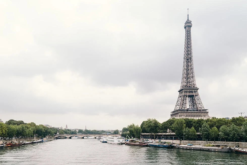 Effiel tower next to body of water with cloudy skies