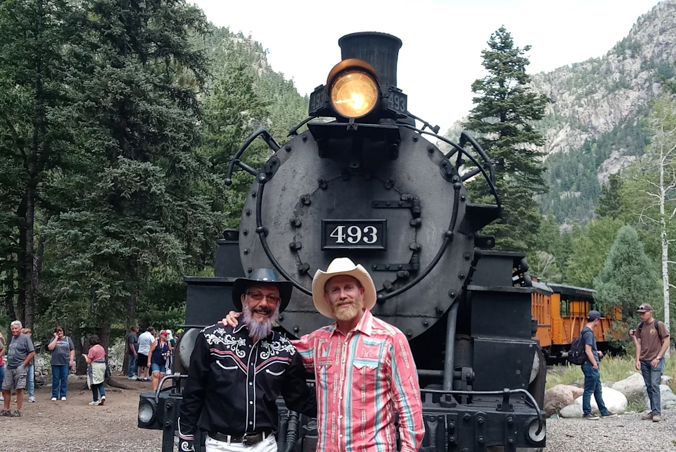 Cesar posing with a friend in front of a train
