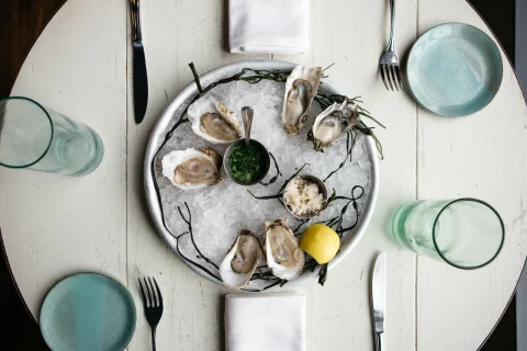 oysters and a small tin of green sauce on a bowl of ice