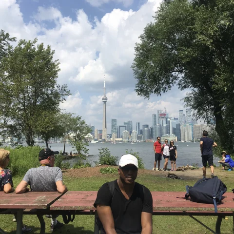 People chilling near a lake with high buildings on the other side 