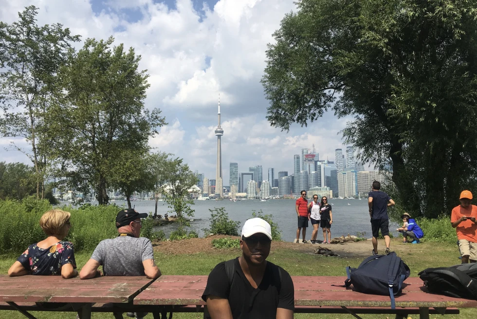 People chilling near a lake with high buildings on the other side 