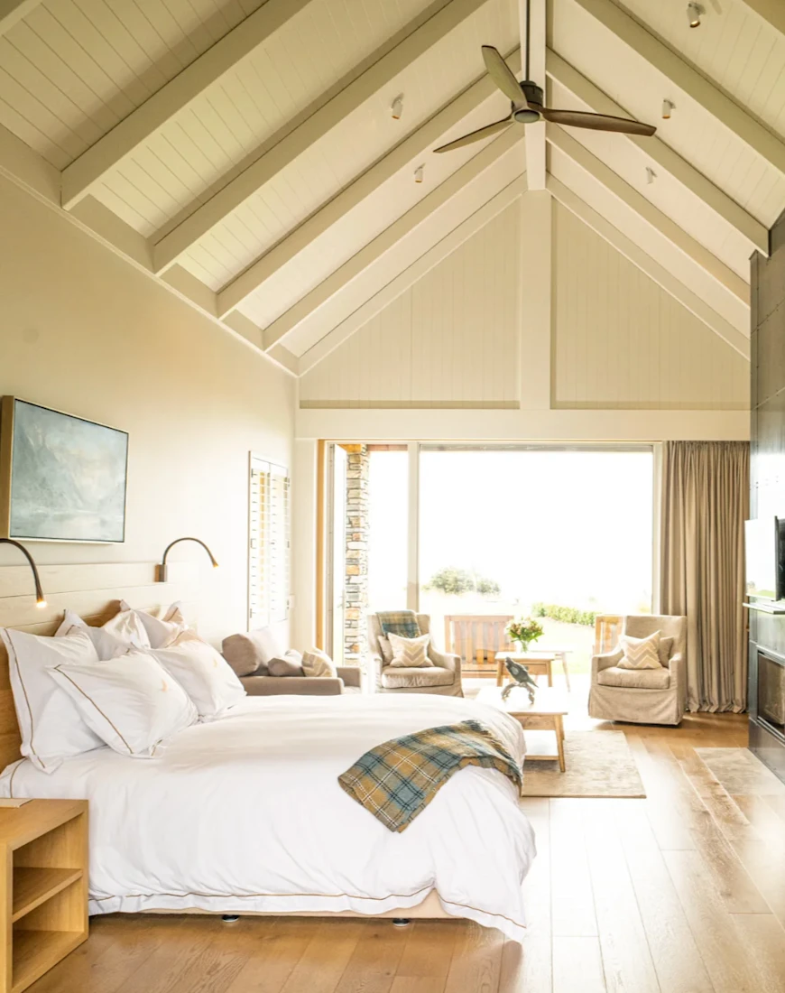 a large white bed in a sunlit bedroom with an A-shaped ceiling