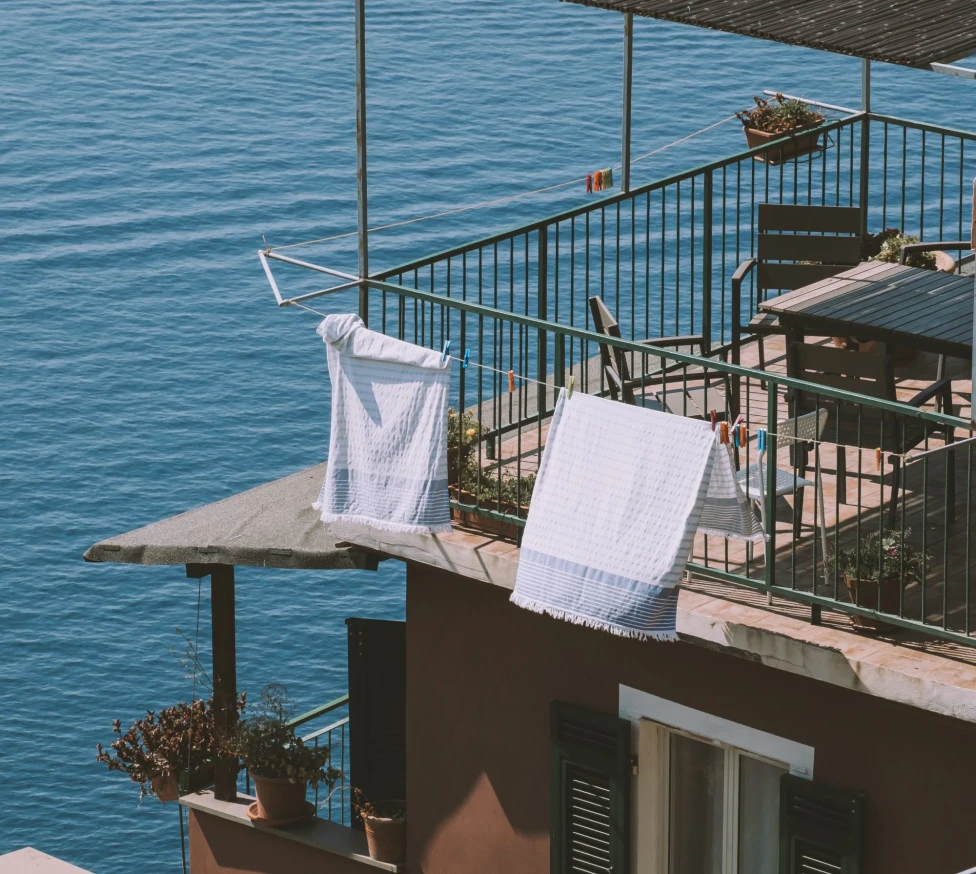 Clothes hanging out to  dry on a balcony over a body of water. 