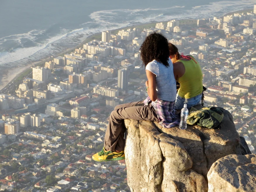 Two girls sitting on a rock overlooking Cape Town from Table Mountain. 