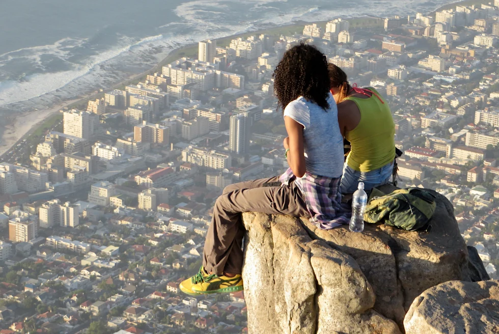 Two girls sitting on a rock overlooking Cape Town from Table Mountain.
