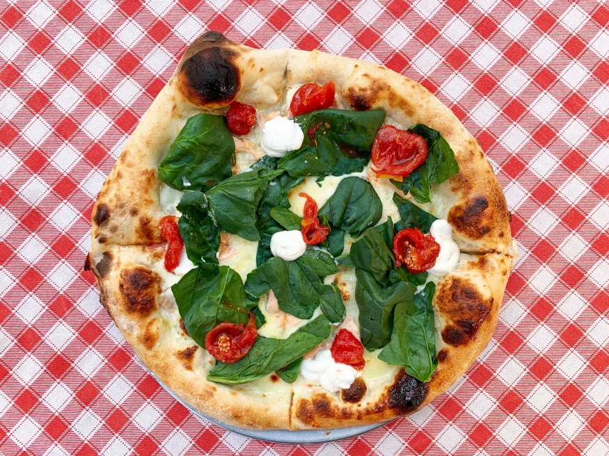 pizza with basil on checkered tablecloth