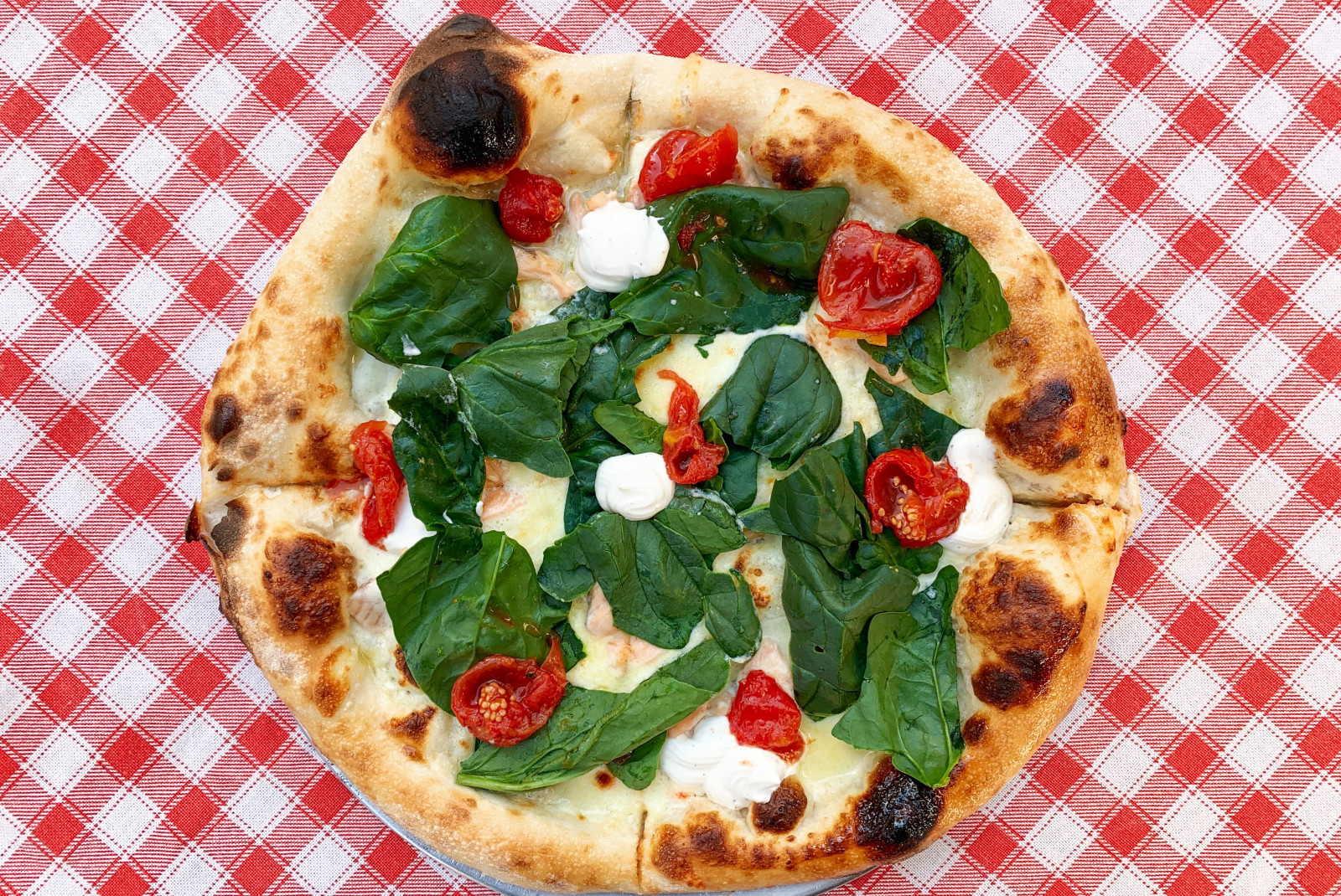 pizza with basil on checkered tablecloth