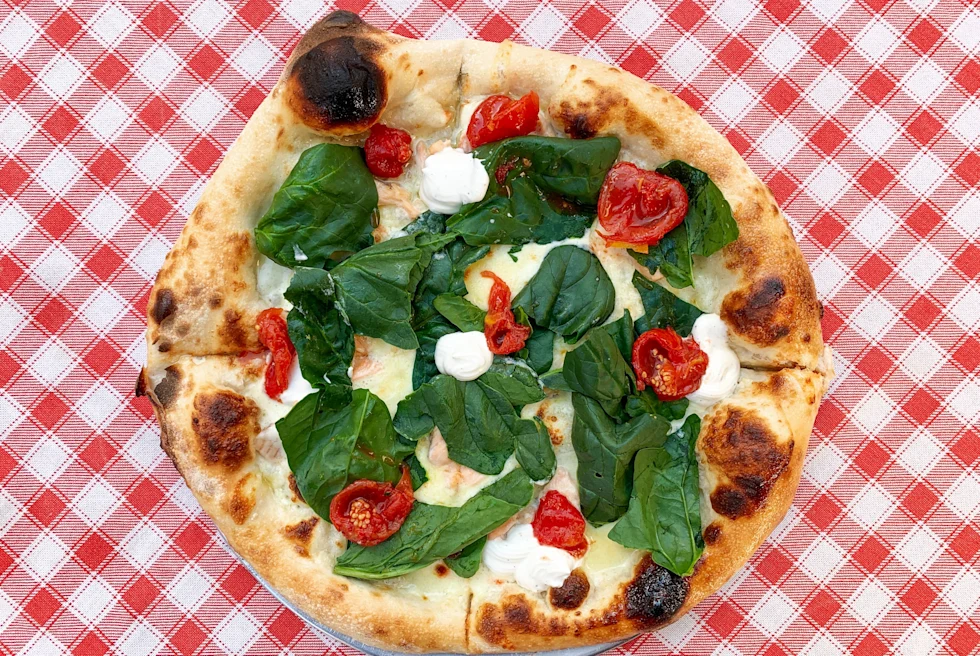 pizza with basil on checkered tablecloth