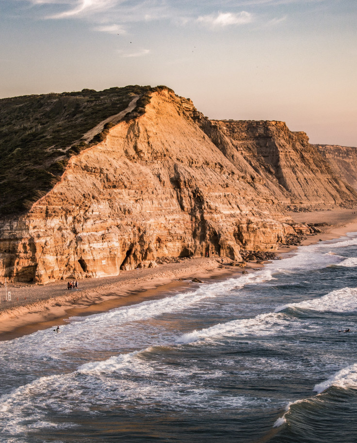 body of water next to cliff during sunset