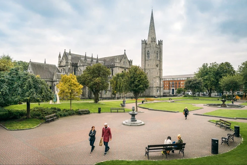 A park with a fountain and a church like building.