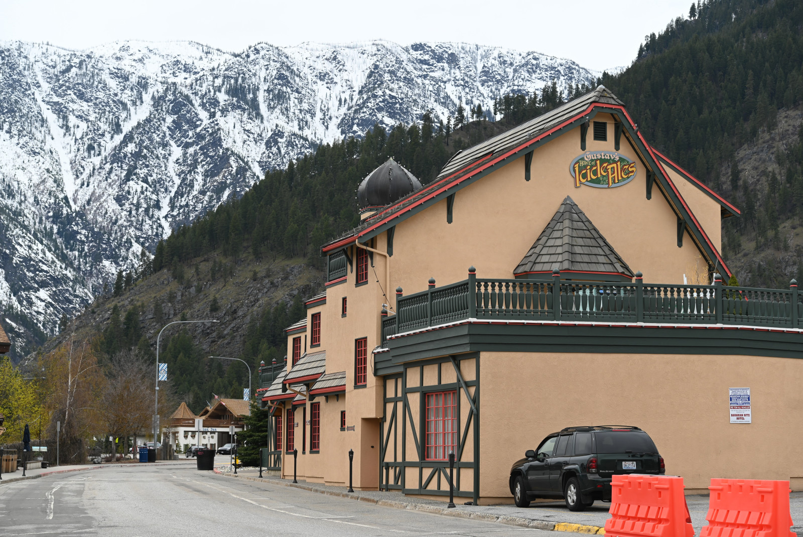 Tan building next to road with trees and snowy mountains in background