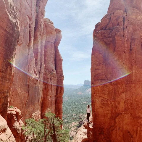A person hiking on a trail between two red rock cliffs near one of the best resorts in Sedona AZ for couples.