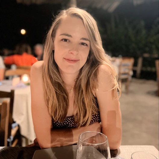 Travel Advisor Sarah Howard in a black top sitting at a table with wine in front of her.