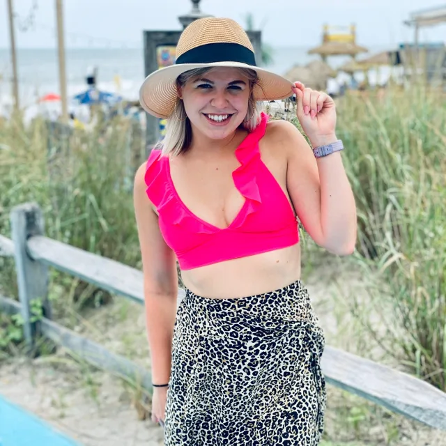 Travel Advisor Eleni Klesaris in a pink cropped tank top , zebra printed skirt and a beach hat. 