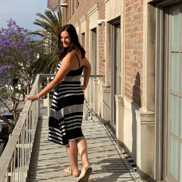 Travel Advisor Trina Hendry in a black and white striped dress in front of a brick wall.