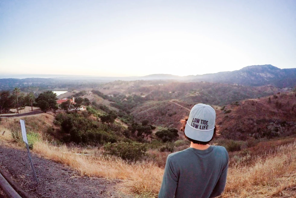 A man hiking mountains in California in a cap.
