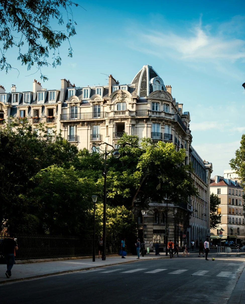 A street in the Paris 3rd arrondissement, with a large Hausmannian building next to a green park.