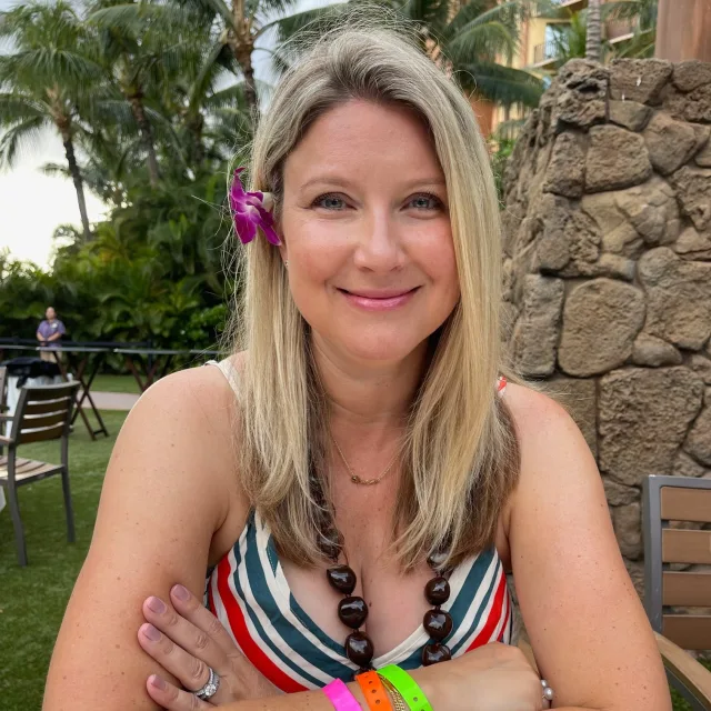 Travel Advisor Katrina Frank sitting outside in Hawai'i with a purple flower in her hair.