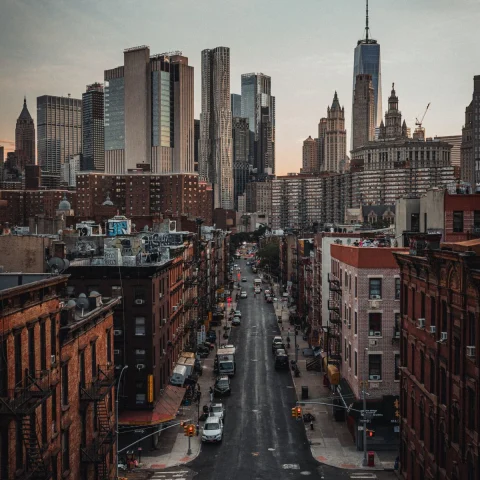 cars parked on a street overlooking New York City's skyline