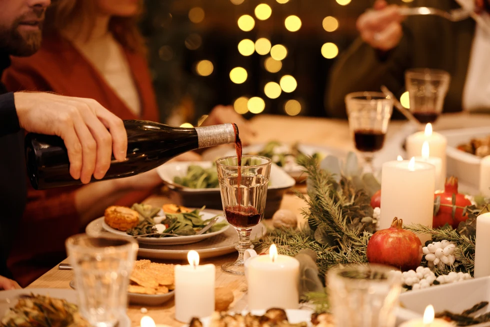 A decorated dining table being served red wine. 