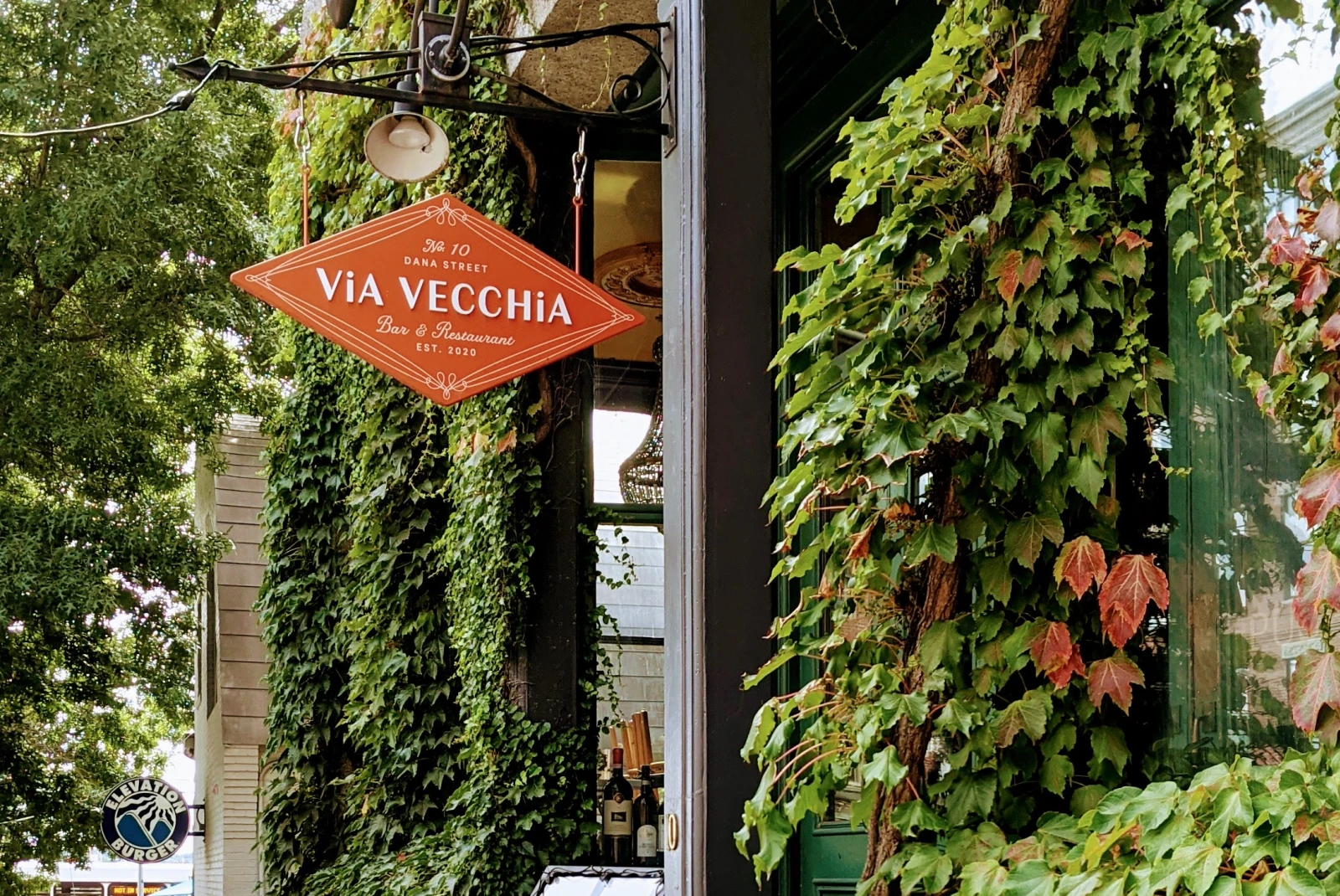 Green vines on side of building with orange sign during daytime