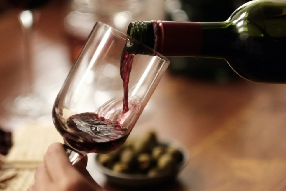 hand pouring red wine into a wine glass