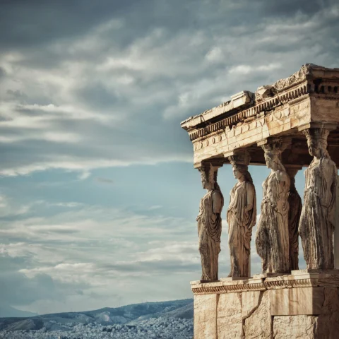 A view of an Ancient Greek statue with clouds in the background. 
