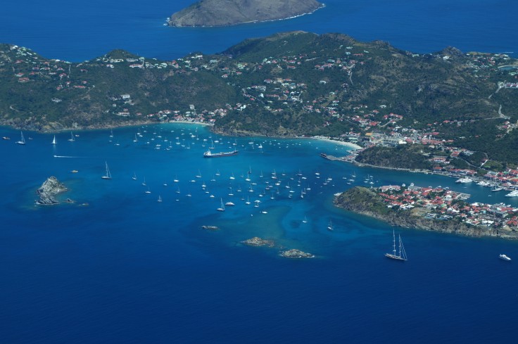 aerial view of saint kitts and nevis large blue ocean with multiple white boats and a large green land mass with pockets of homes