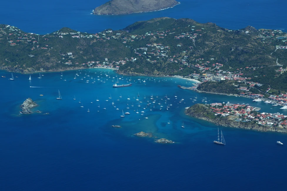 aerial view of saint kitts and nevis large blue ocean with multiple white boats and a large green land mass with pockets of homes