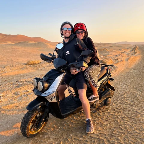 A man and woman on a motorcycle in a dessert. 