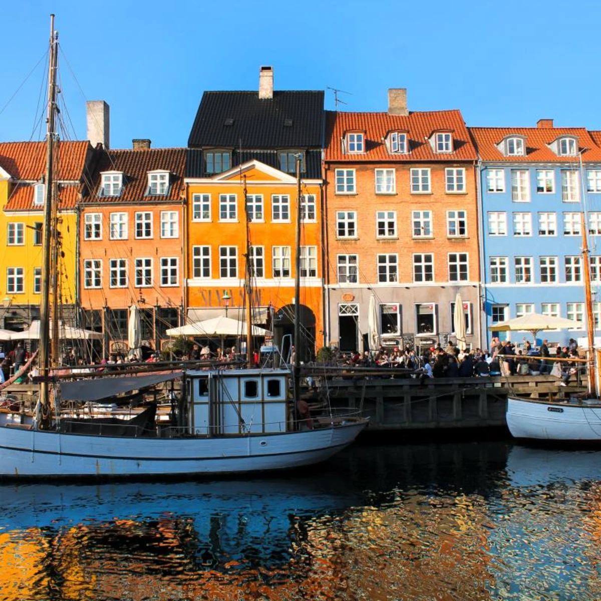 Sailboats in the water with colorful buildings in the background in Denmark