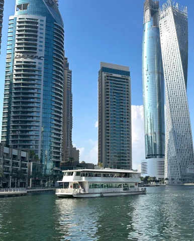 Boat and tall buildings at Dubai Marina on a sunny day.