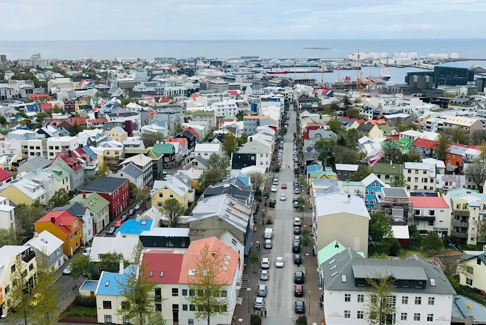 Aerial view of city with colorful buildings and harbor at the back.