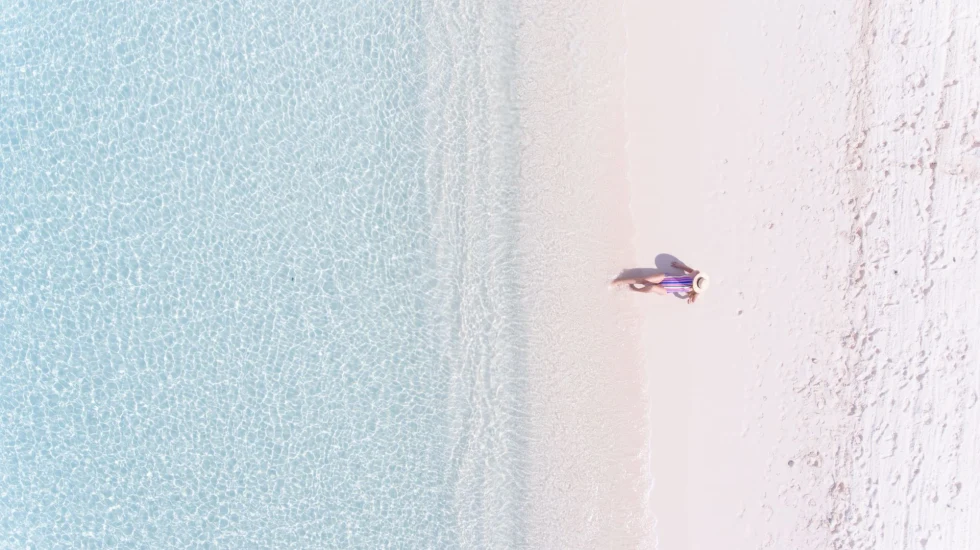 a woman lounges on a pristine white sand beach