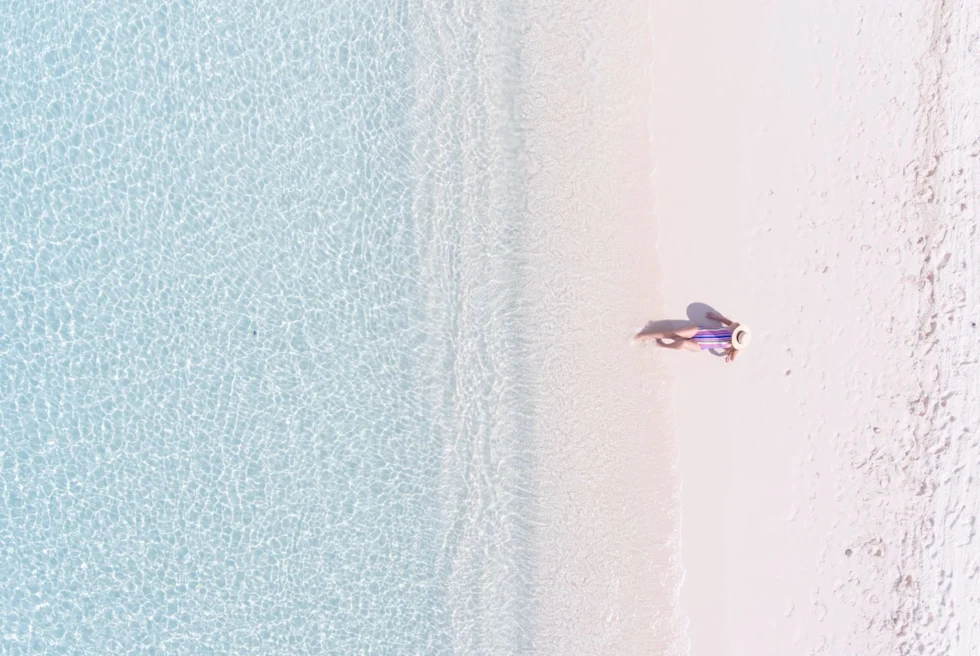 a woman lounges on a pristine white sand beach