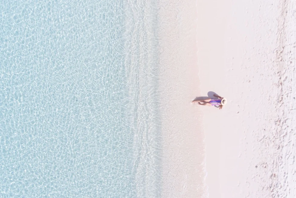 a woman lounges on a pristine white sand beach