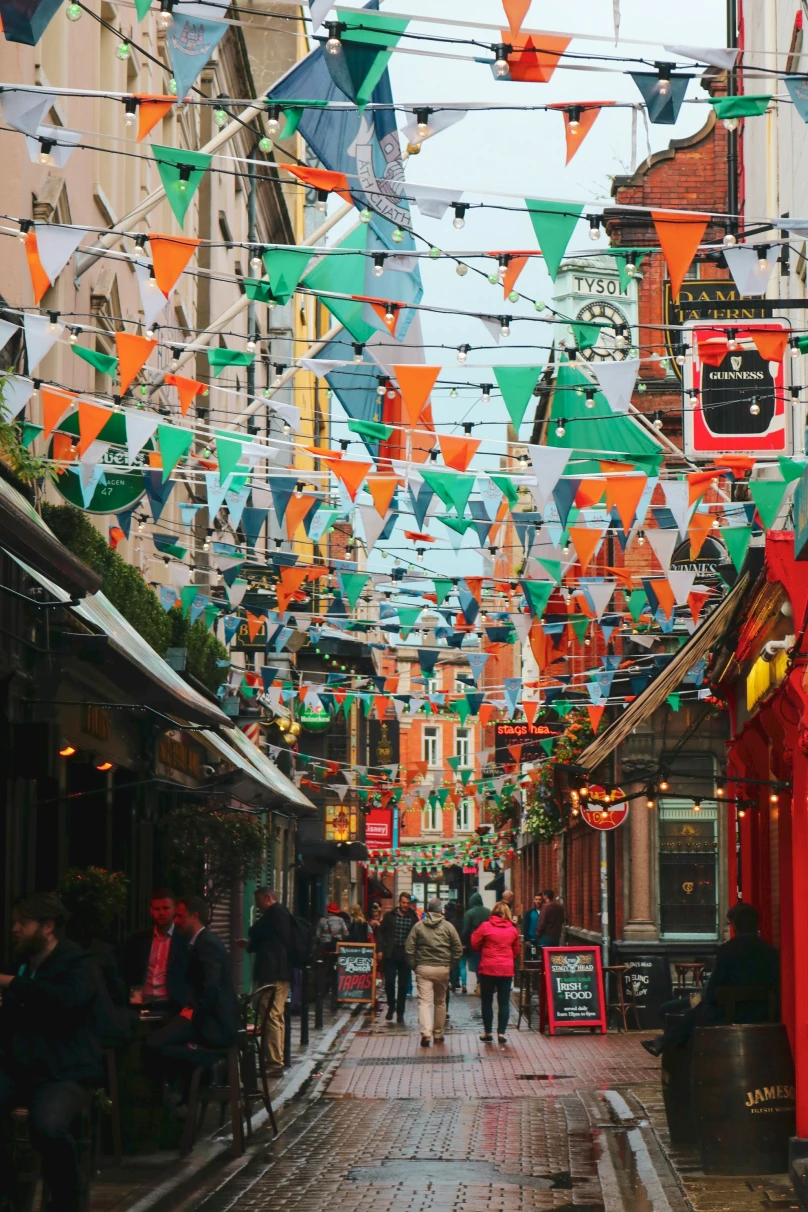 An alleyway between buildings with green and orange triangle bunting flags