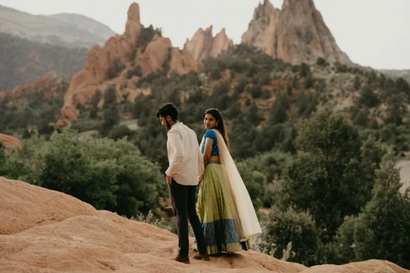 Couple holding hands walking on cliff over red rocks in Colorado Springs in the US.