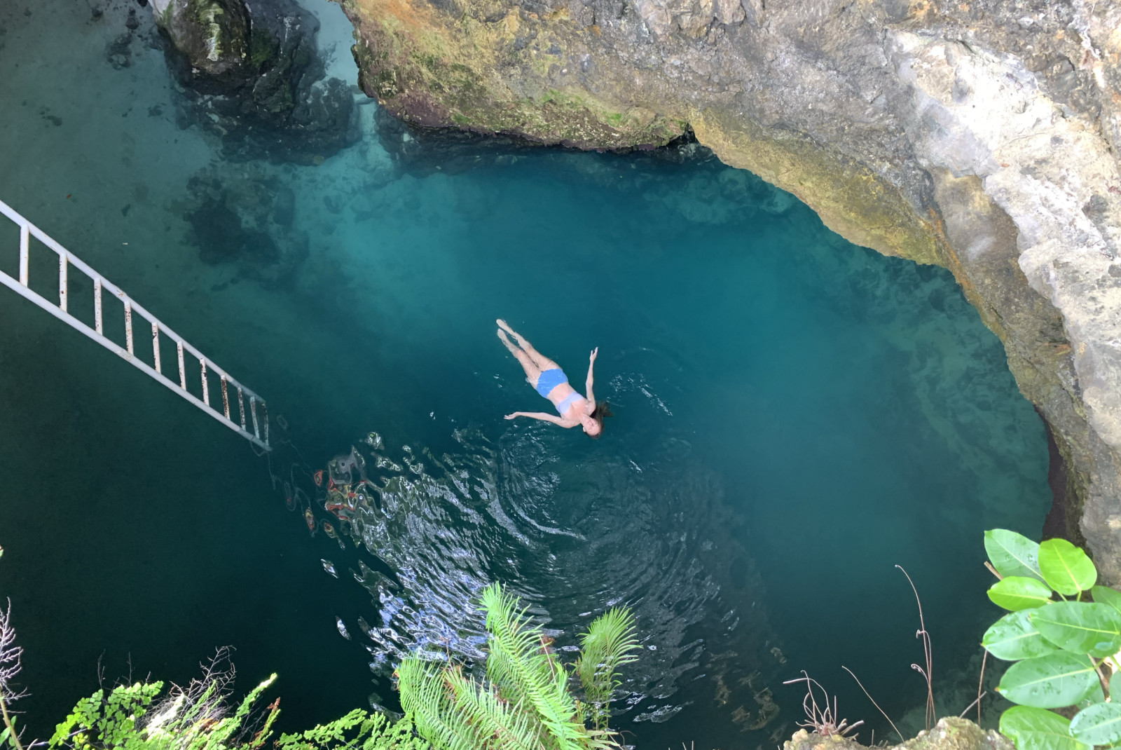 View from above of a woman swimming in the Blue Hole in Jamaica