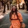 Woman standing on balcony outside and smiling while holding a drink