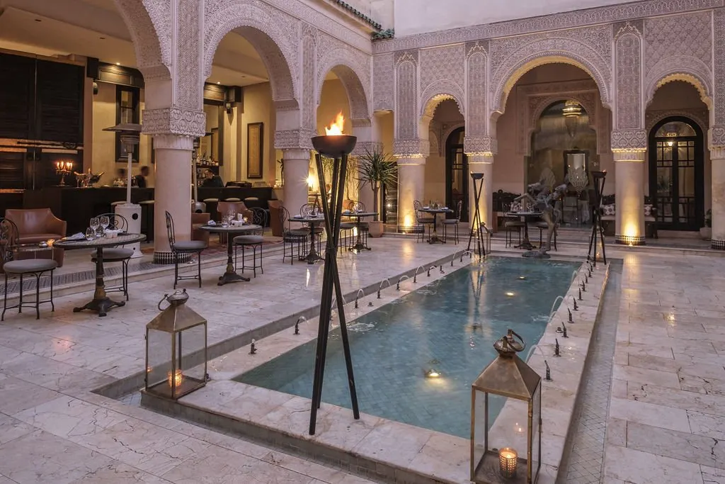 a small rectangular reflection pool in a chic courtyard with curved arches