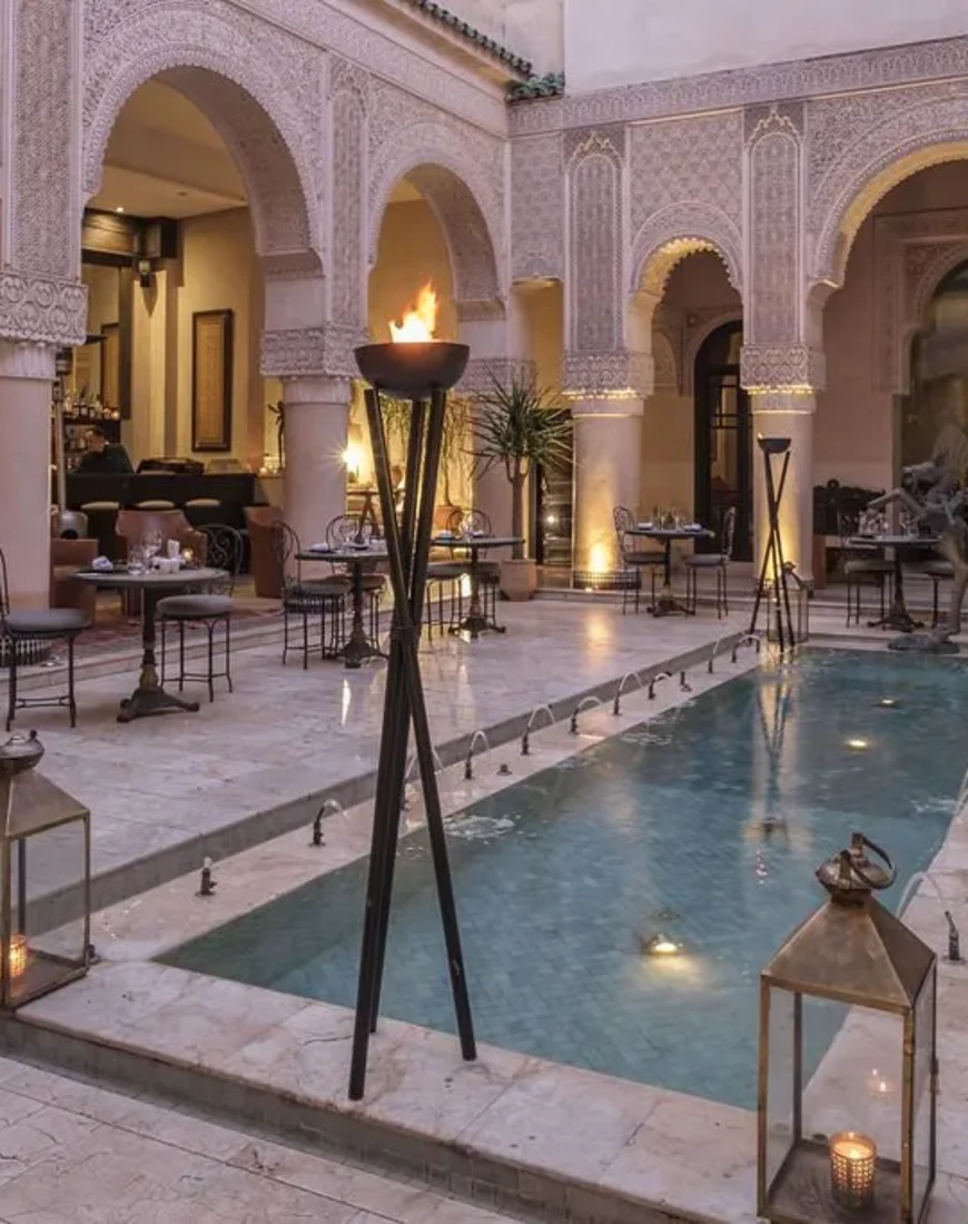a small rectangular reflection pool in a chic courtyard with curved arches