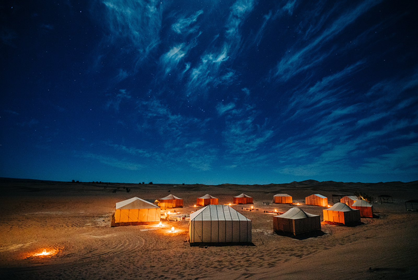 Morocco Sahara desert campfire white tents clue sky with clouds and sand