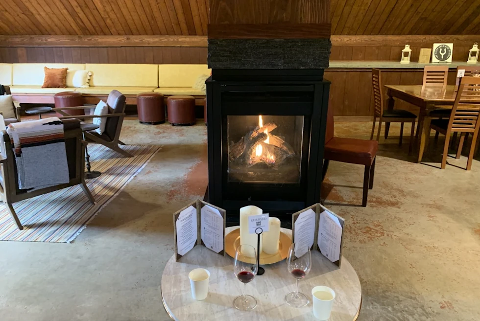 old fireplace with 2 glasses of red wine set on the small wooden table in a sitting room